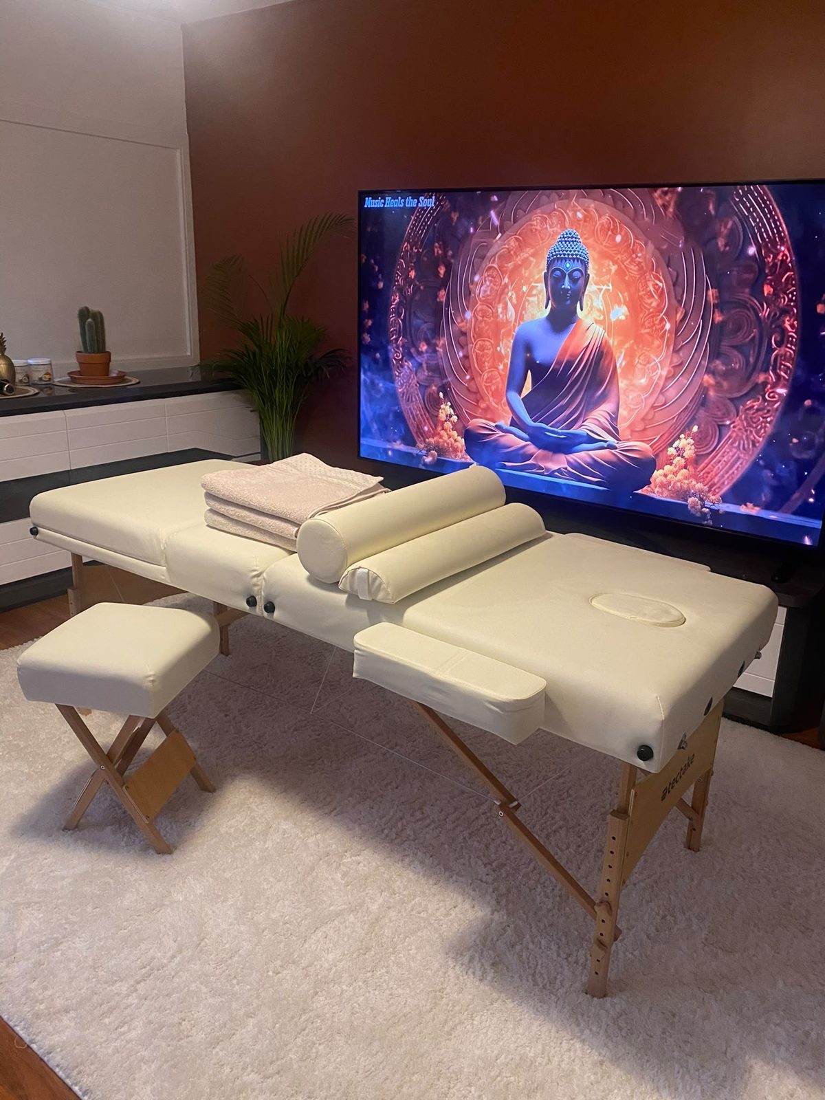 Table de massage avec serviettes propres et coussins, dans une pièce chaleureuse